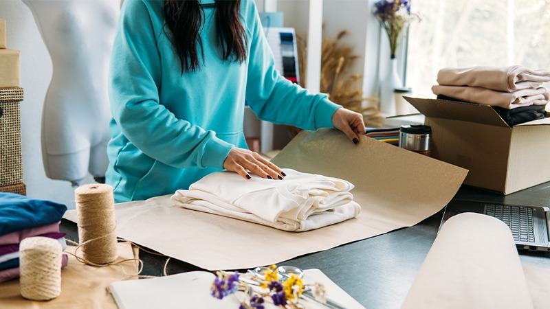 یک خانم در حال بسته‌بندی لباس در کاغذ-cloth-pack