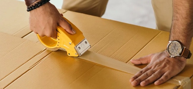 فردی در حال چسب زدن به بسته-packaging