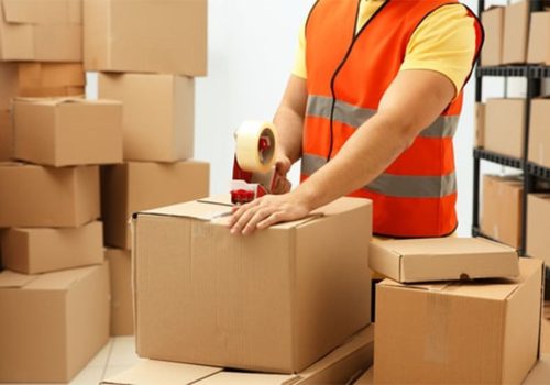 چند کارتتن مقوایی و یک فرد در حال بستّ بندی-بهترین روش بسته بندی کالا